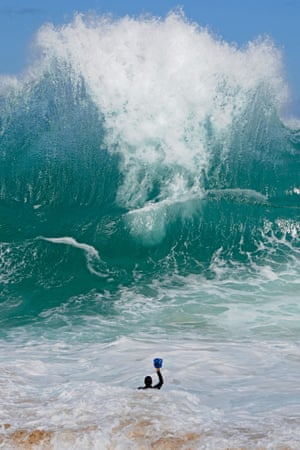 Photographer Clark Little facing a giant wave with his camera, in Oahu, Hawaii.  A photographer wades into the ocean to capture the beauty of breaking waves as they roll over him. Hawaii-born Clark Little uses a camera encased in a waterproof box, which he attaches to his leg with a harness to capture stunning images of the breaking water. The 44-year-old now travels to some of the world's most picturesque spots in pursuit of the perfect wave.