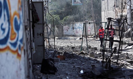 Palestinian medics walk past destroyed houses in the  Gaza City neighbourhood of Shujai’iyaduring