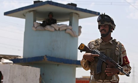 An Iraqi soldier stands guard at a checkpoint in the Iraqi town of Taji