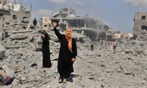 A Palestinian woman chants slogans in support of Palestinian fighters as she stands next to her destroyed house in Beit Hanoun town.