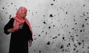 A Palestinian woman looks at a shrapnel-scarred wall at the hospital in Beit Hanoun town.