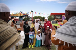 A family has their photograph taken after morning prayers during an Eid celebration in Burgess Park in London, England. The Muslim holiday Eid marks the end of 30 days of dawn-to-sunset fasting during the holy month of Ramadan.