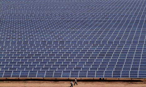 Indian workers walk past solar panels at the 200 megawatts Gujarat Solar Park at Charanka in Patan district, India, Saturday, April 14, 2012.