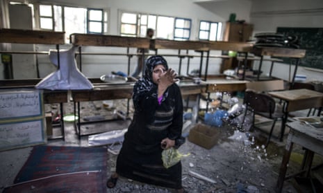 A desperate Palestinian woman throws debris in the air at the classroom where she is taking shelter with her family on July 30, 2014 following Israeli army shelling in the area. An Israeli shelling on the UN school being used as a shelter in the northern Gaza Strip killed 20 people today, medics said. 