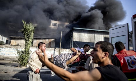 Palestinian emergency personnel evacuate a wounded man following an Israeli air strike on a market place in the Shejaiya neighbourhood near Gaza City, on July 30, 2014.