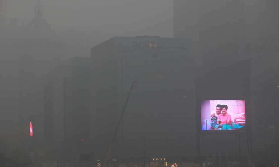 A big screen flashes commercials on the exterior of an office building in Xi'an in northwest China's Shaanxi province 15 December 2012 as  air quality index reaches 282 due to pollution.