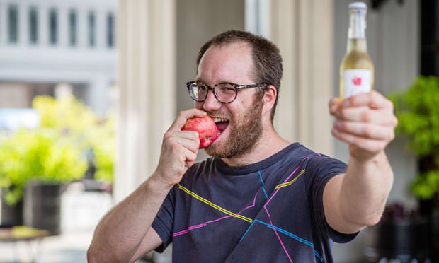 Bar owner Jozef Czarnocki bites an apple and holds a bottle of cider in defiance of Russia's ban