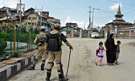 A Kashmiri family walks past Indian paramilitary troopers in Srinagar