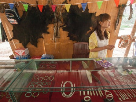 A woman is seen selling ivory products with two bear skins flanking a wild cat skin behind her on the wall, at an exotic wildlife restaurant for Chinese tourists in the town of MongLa, Shan State Special Region Four, Burma, 04 April 2014.