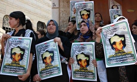Women from Mohammed Abu Khdeir's family hold pictures of the killed Palestinian teenager