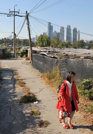 A school girl walks along a road lined with a shacks. The illegal encampment grew up on private land in 1988.