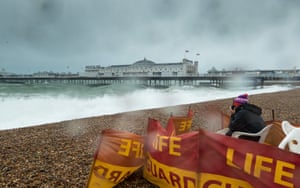 A lifeguard stands watch over the empty beach in Brighton.