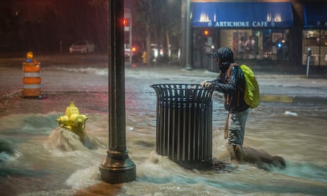 A pedestrian hangs on to a trash can along Central Avenue as rainwater flows towards downtown Albuquerque, N.M.,  August 1, 2014.  Heavy rains late Friday night caused the flash flooding and road closures in parts of downtown and in other areas.