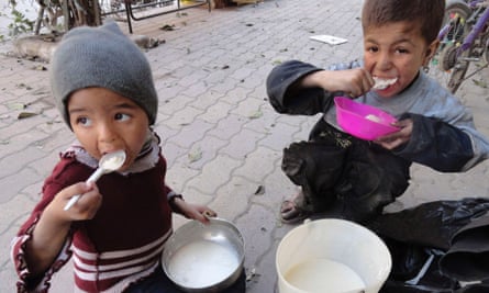 Children eat food distributed to them in the besieged al-Yarmouk camp, south of Damascus April 7, 2014.