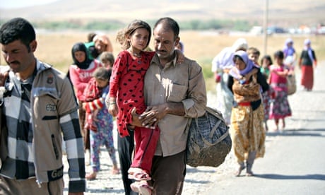 A displaced Yazidi Iraqi carries his daughter as they cross the Syrian border at Fishkhabour. 