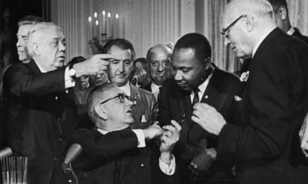 US President Lyndon B Johnson shakes the hand of Dr. Martin Luther King Jr at the signing of the Civil Rights Act while officials look on, Washington DC.