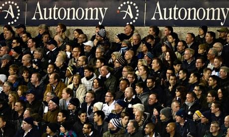 Tottenham Hotspur fans watch their team, beneath an Autonomy advertising hoarding