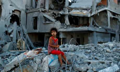 A girl sits on the ruins of her family's home in Gaza