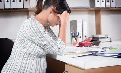 Young pregnant woman sitting at desk