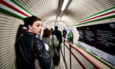 A woman looks back while walking down a hallway connecting two tube stops in the London Underground