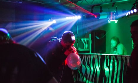 A man inhales nitrous oxide from a balloon at a warehouse rave in east London.