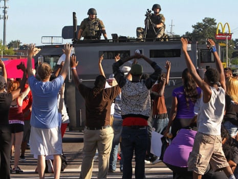 Protesters raise their hands in front of armed police in Ferguson.