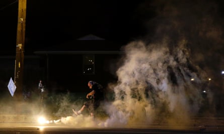 A protester kicks a smoke grenade deployed by police back in the direction of police.