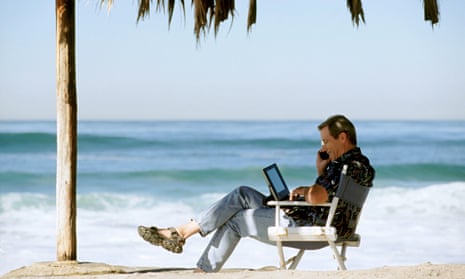 man using laptop and phone on beach