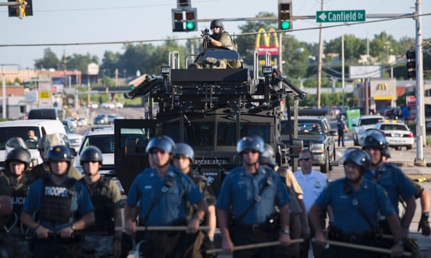 Riot police stand guard before an armoured vehicle and a police armed with a mounted sniper rifle in Ferguson, Missouri.