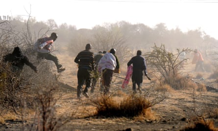 Striking mine workers run for cover after police officers open fire outside the Nkageng informal settlement on 16 August, 2012, in Marikana.