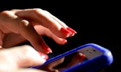 A womans hands close up with red painted finger nails holding a smart phone