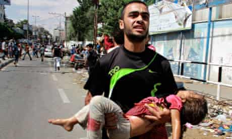 A Palestinian man carries a child killed in the blast outside a UN run school in Rafah, in the south