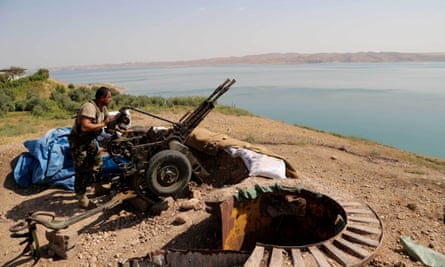 A Kurdish peshmerga fighter prepares his weapon at his combat position near the Mosul Dam at the town of Chamibarakat outside Mosul, Iraq. Kurdish forces took over parts of the largest dam in Iraq on Sunday less than two weeks after it was captured by the Islamic State.