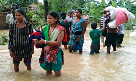 Nepalese villagers carry their belongings through flooded streets 