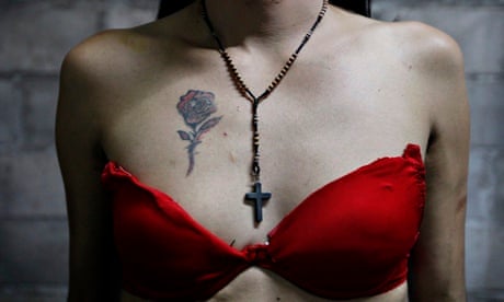 Transgender Bessy displays a flower tattoo and crucifix on her chest in Tegucigalpa