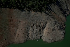 A boat is dwarfed by the steep banks of Lake Oroville.