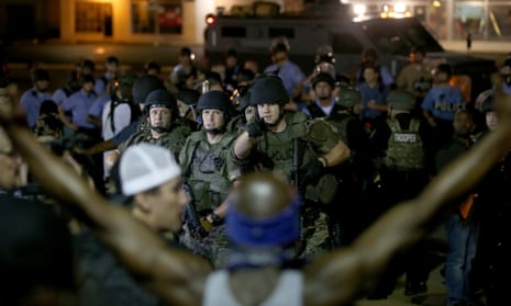 Police point to a demonstrator who has his arms raised before arresting him on 19 August in Ferguson.