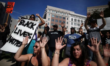 Demonstrators hold their hands up during a moment of silence 14 August in Oakland, California.
