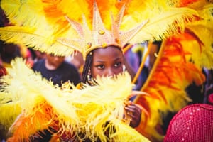 a girl performing at the notting hill carnival covering her face with her costume