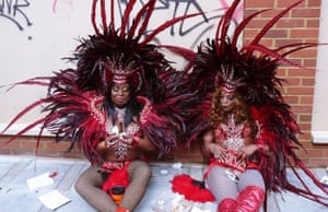 women in carnival costume sitting on the street resting against a wall