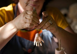 Gail Grainger, who has been a doll restorer for 14 years, adds fingers to a damaged doll’s hand in her workshop.
