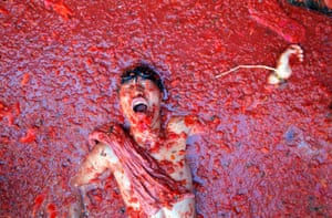 A man lies in a puddle of squashed tomatoes at La Tomatina festival