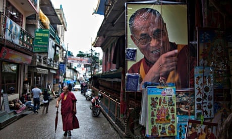 A Buddhist monk walks past a stall selling portraits of the Dalai Lama in Dharmsala, India