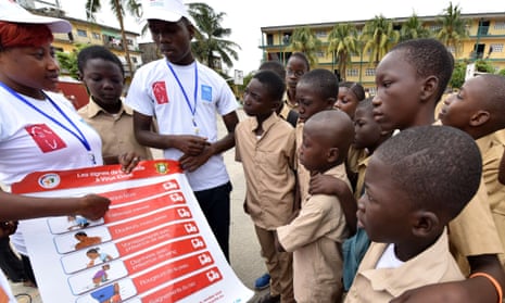 United Nations Development Programme volunteers show a placard about Ebola symptoms  to school students in Abidjan, Ivory Coast.