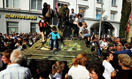 Children play on a separatist military vehicle in Lugansk as residents welcome back fighters