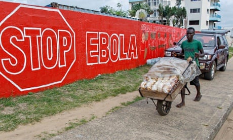 A Liberian man passes a mural raising awareness of Ebola