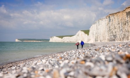 A couple walking along the pebble foreshore at Birling Gap, East Sussex