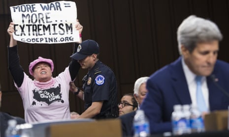 A protestors from the group CodePink holds up a sign as US Secretary of State John Kerry testifies.