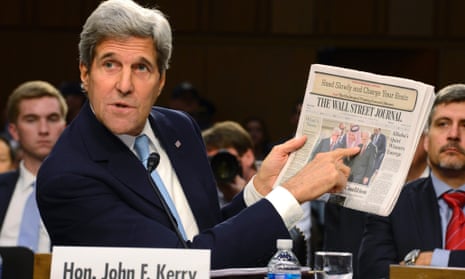 US Secretary of State John Kerry holds up a copy of The Wall Street Journal newspaper.