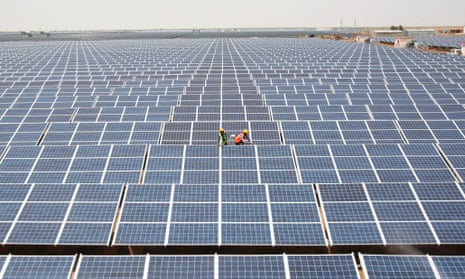 Workers install photovoltaic solar panels at the Gujarat solar park.